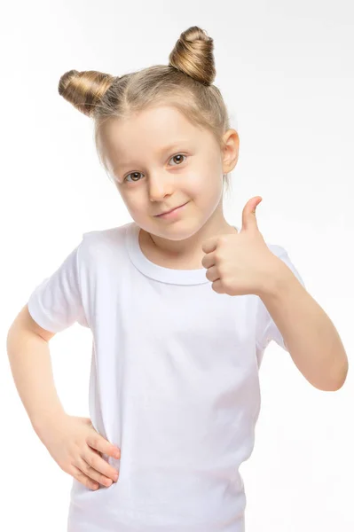 Little blonde girl shows like in a white T-shirt on a white background. — Stock Photo, Image