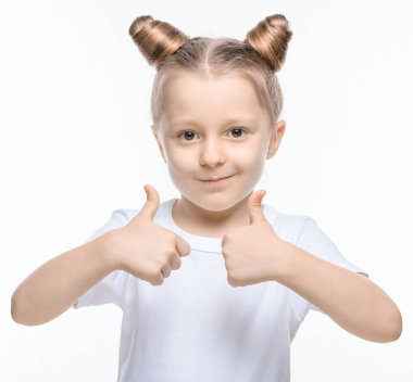 Beyaz tişörtlü küçük sarışın bir kız beyaz arka planda iki eli olan birini gösteriyor..