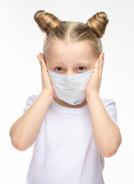 Tıbbi maske takmış sarı saçlı hasta küçük bir kız elleriyle başını tutuyor. Tıbbi epidemiyolojik dönem, solunum hastalıkları ve yüksek sıcaklık kavramı.