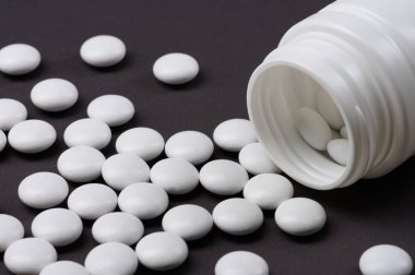 Beyaz tabletler, vitaminler ya da gıda katkı maddeleri siyah üniformalı beyaz bir baloncuktan dökülüyordu..