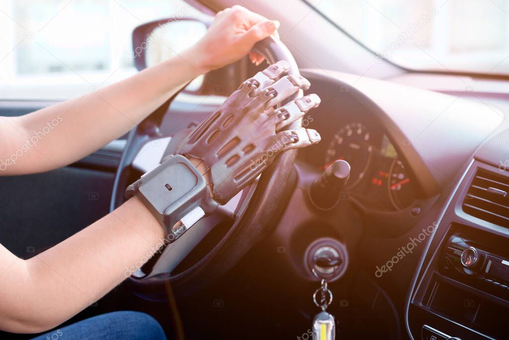 A person with a prosthetic hand printed on a 3d printer at the wheel of a car. Concept of practical application of 3D printing.