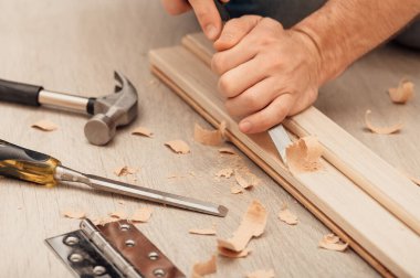 Kapı menteşesini kapı çerçevesine kendi ellerinizle monte etmek, bir el aleti kullanarak, yakın çekim.