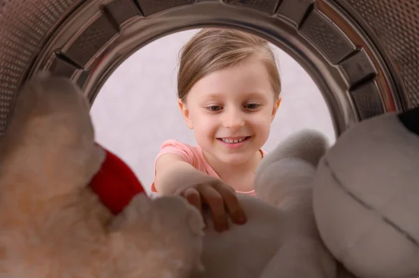 Szczęśliwa Dziewczynka Wyciąga Pralki Czyste Miękkie Zabawki Koncepcja Potrzeby Okresowego — Zdjęcie stockowe
