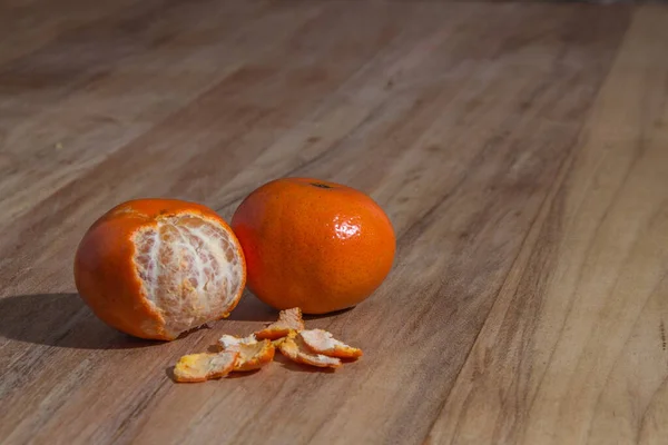 木製テーブルの上にオレンジ色の皮をむいたみかん — ストック写真