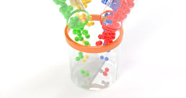 Gekleurde ballen vallen in een glazen mandje. — Stockvideo