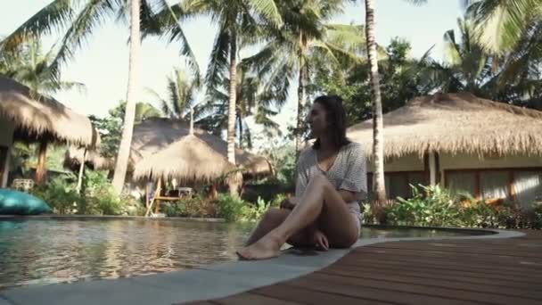Jonge Mooie Vrouw Zittend Aan Het Zwembad Kijkend Naar Schoonheid — Stockvideo