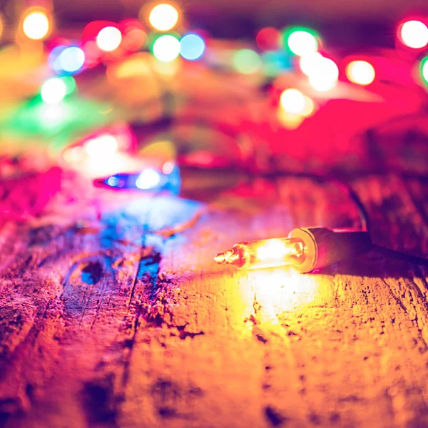 Christmas blurred colorful lights on dark wooden background. Dec — Stock Photo, Image
