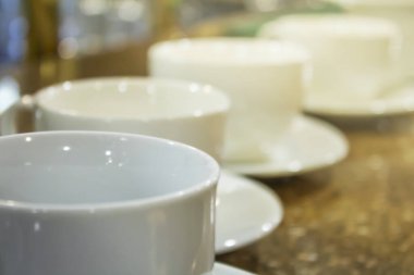 Masada ve kafenin arkasında bir sürü beyaz kahve fincanı var..