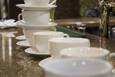 Masada ve kafenin arkasında bir sürü beyaz kahve fincanı var..