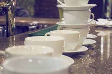 Masada ve kafenin arkasında bir sürü beyaz kahve fincanı var..