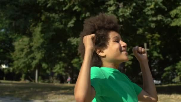 Glädjande skolpojke visar framgång gest höja händerna upp, seger fest — Stockvideo