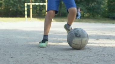 Futbol ayakkabısı giymiş erkek bacakları sahada topa vuruyor, sokak yarışması spor oyunu