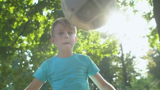 Niño masculino activo pateando pelota jugando al aire libre, hobby de verano, deporte — Vídeo de stock