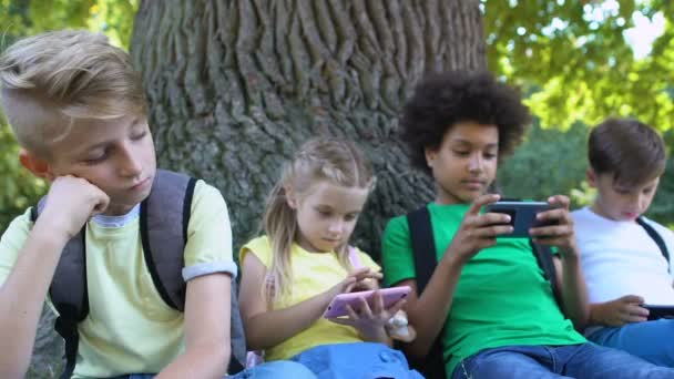 Грустный ребенок смотрит на друзей прокрутки смартфонов чувство скуки, общение — стоковое видео