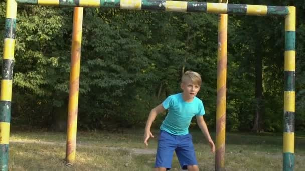 Menino jogando futebol, tentando pegar bola, tempo livre de verão, atividade esportiva — Vídeo de Stock