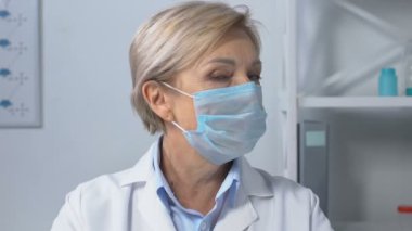 Ciddi kadın doktor kameraya bakıyor, salgın hakkında endişeli.