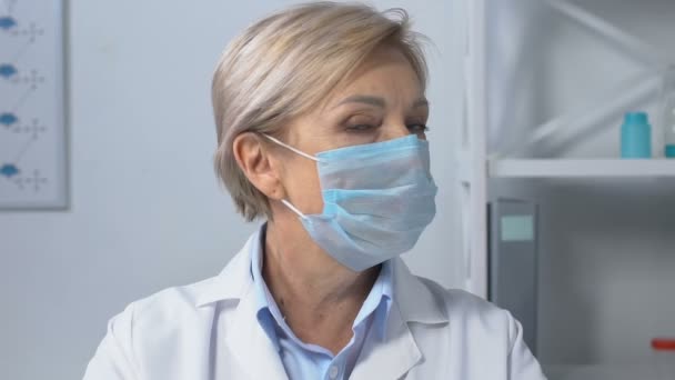 Grave medico femminile in maschera viso guardando la fotocamera, preoccupato per l'epidemia — Video Stock