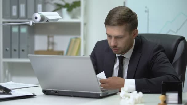 Плохой бизнесмен чихает в тканях во время работы на ноутбуке в офисе, грипп — стоковое видео