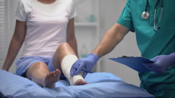Γιατρός έλεγχο τραυματισμένων ασθενών πόδι σε ελαστικό περιτύλιγμα, γραπτώς αποτέλεσμα της εξέτασης — Αρχείο Βίντεο