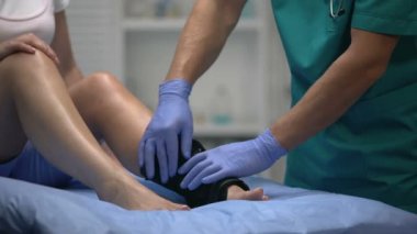 Doktor iki kayışlı bilek sargısını uygun pozisyonda düzeltiyor. Anti-inflamatuar ilaçlar.