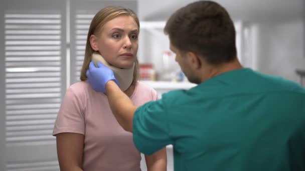 Ortopedista verificando a posição do colar cervical de espuma feminina, informando o diagnóstico — Vídeo de Stock