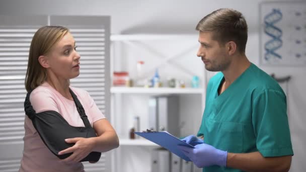 Femme dans le bras fronde informant le médecin avec la forme médicale sur les bons résultats de réadaptation — Video