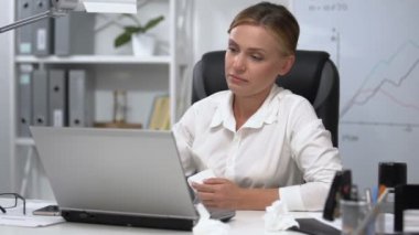 Ellerinde peçete olan ofis kadını hapşırıyor, gözyaşı döküyor, alerjisi var.