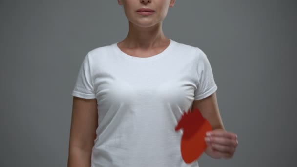 Mujer preocupada sosteniendo un signo cardíaco de papel, prevención de derrames cerebrales y ataque cardíaco — Vídeo de stock