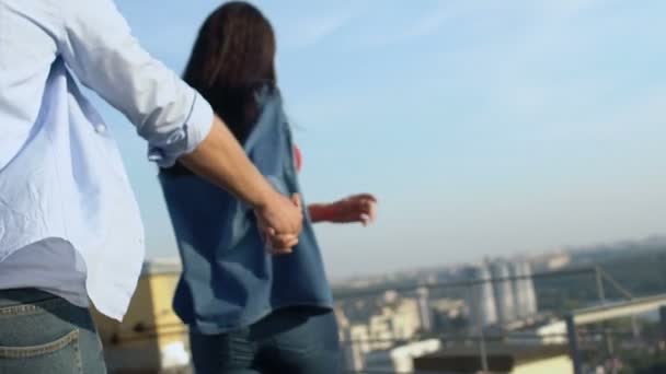Amor casal de mãos dadas correndo para desfrutar de paisagem urbana no telhado, verão romântico — Vídeo de Stock