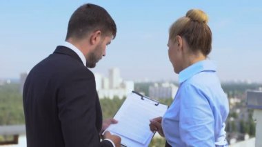 Erkek ve kadın avukatlar sözleşme detaylarını dışarıda, ofis işinde, kariyerde tartışıyorlar