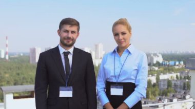 Takım elbiseli seminer katılımcıları dışarıda kameraya bakıp konferans veriyor.