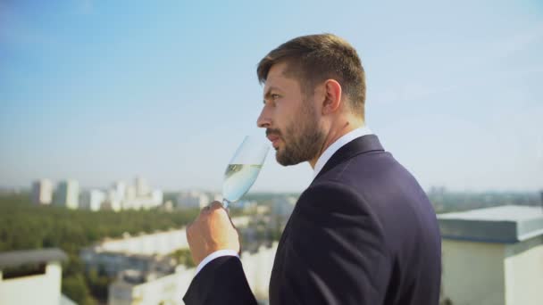 Грустный молодой бизнесмен пьет алкоголь из стекла на открытом воздухе, проблемы на работе, кризис — стоковое видео