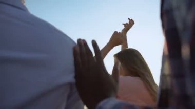 Genç çok ırklı arkadaşlar müziğin ritmini hissediyorlar, açık hava festivalinde dans ediyorlar.