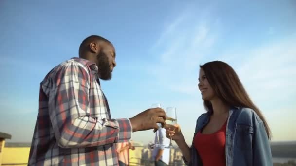 Молодая многонациональная пара пьет шампанское и знакомится на вечеринке на крыше — стоковое видео