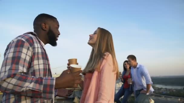 Mnohostranný pár se směje a flirtuje na střeše, tráví čas s přáteli — Stock video