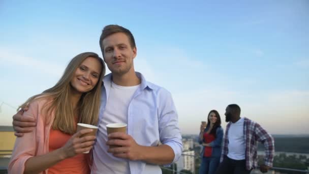 Abrazando pareja caucásica sonriendo a la cámara, pasando tiempo juntos en la fiesta en el techo — Vídeos de Stock