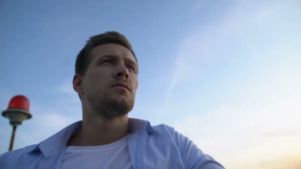 Tänksam vit man står mot himlen bakgrund, tänker på livet — Stockvideo