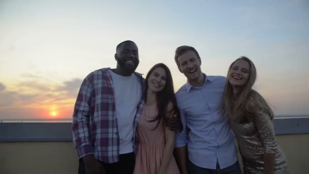 Grupo multirracial de amigos abrazándose y sonriendo a la cámara, de pie en la terraza — Vídeo de stock