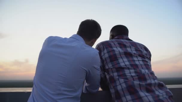 Multietnické mužské přátelé mluví na terase večer, soukromý rozhovor — Stock video