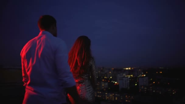 Нежные обнимашки, мужчина показывает девушке городской пейзаж с крыши, романтика — стоковое видео