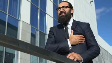 Orta yaşlı, takım elbiseli bir adam göğüs ağrısı çekiyor, kalp krizi geçiriyor.