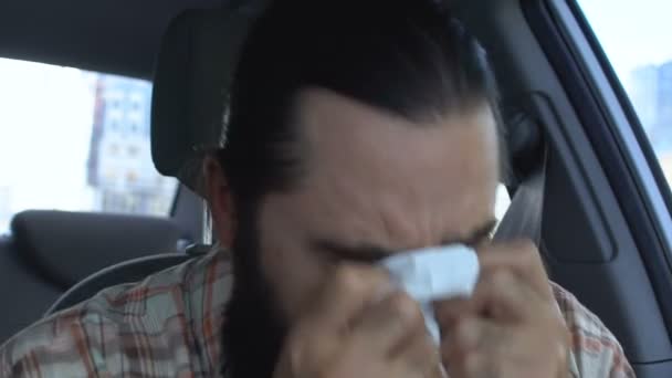 Хворий чоловік чхає в автомийці з серветкою, епідемією респіраторних захворювань — стокове відео