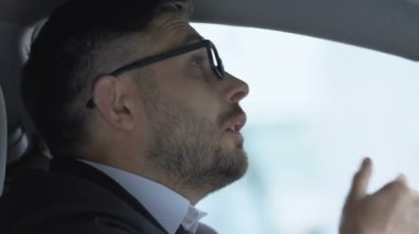 Genç işadamı arabada hapşırıyor, soğuk, zayıf bağışıklık sistemi yüzünden burnu akıyor.
