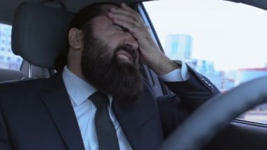 Erkek yüzünde acı, arabada baş ağrısı, çaresiz hisseden üzgün bir adam.