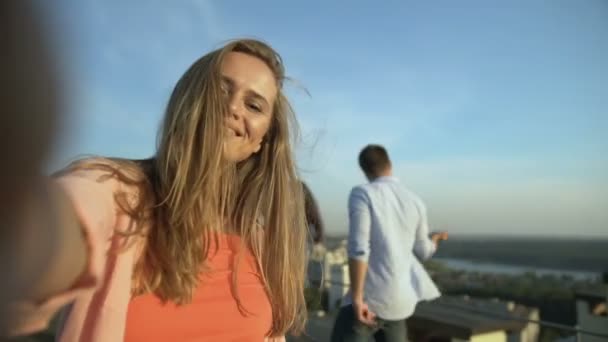 Happy girl biorąc selfie na dachu party, przyjaciele tańczą na tle, relaks — Wideo stockowe