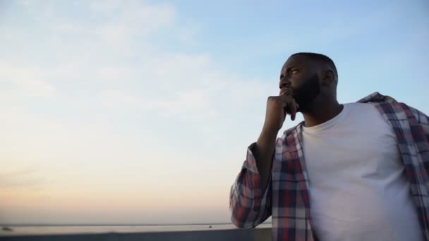 Nachdenklicher afrikanisch-amerikanischer Mann, der sein Kinn berührt, Blick vom Dach — Stockvideo