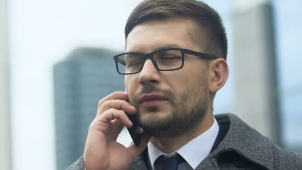 Jovem empresário falando telefone e tendo dor de cabeça ao ar livre, vida estressante — Vídeo de Stock