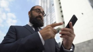 Heyecanlı iş adamı cihaz üzerinde mobil uygulama kullanıyor ve başarı işareti yapıyor, kazanan