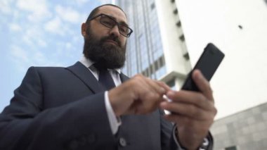 Sinirli işadamı akıllı telefonda mobil uygulama kullanıyor, teknolojiden memnun değil.