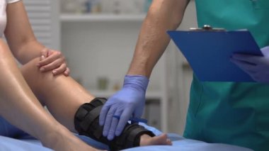 Doktor hasta bacağını ayak bileğine sarıp kontrol ediyor. Kayıt sonuçları, sağlık.